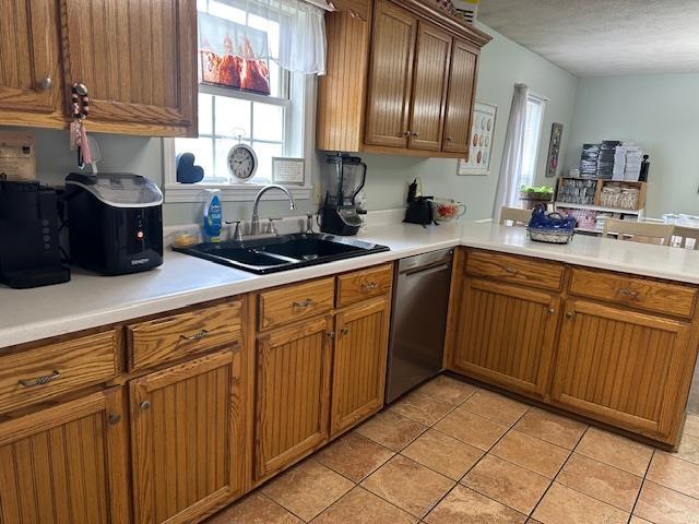 85 Two Boys Rd, Savannah, TN 38372 - kitchen with stainless steel dishwasher, a sink, light tile patterned flooring, and healthy amount of natural light