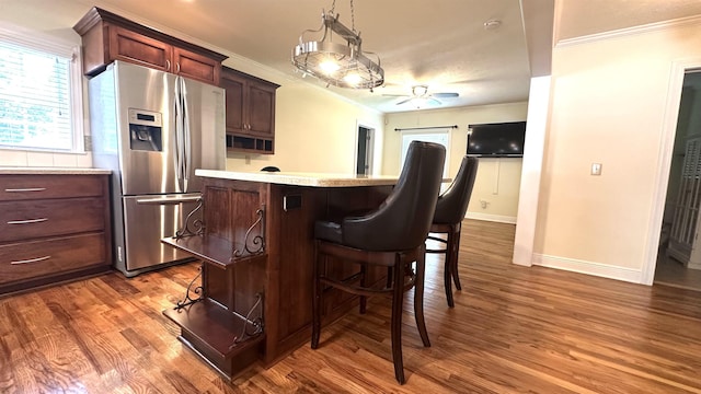bar featuring crown molding, stainless steel fridge with ice dispenser, a ceiling fan, baseboards, and wood finished floors