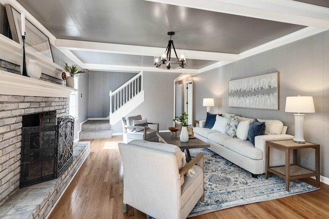 living room with a fireplace, a chandelier, stairs, wood finished floors, and beamed ceiling