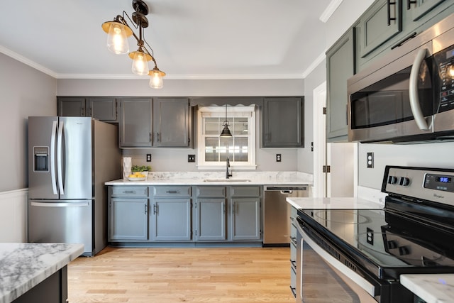 kitchen featuring a sink, ornamental molding, pendant lighting, and stainless steel appliances