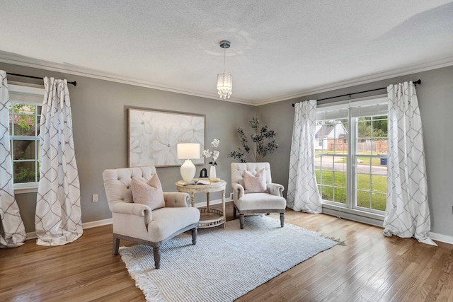living area with crown molding, a textured ceiling, baseboards, and wood finished floors