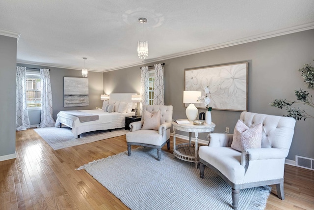 bedroom with crown molding, baseboards, light wood-style floors, and visible vents
