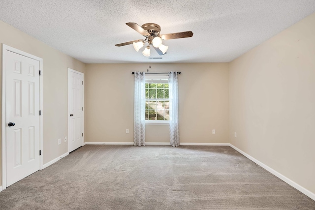 carpeted empty room featuring baseboards, a ceiling fan, a textured ceiling, and visible vents