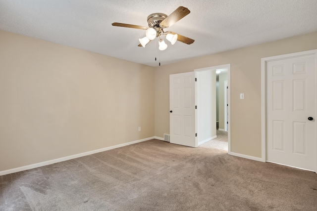 unfurnished bedroom with ceiling fan, carpet floors, a textured ceiling, baseboards, and visible vents