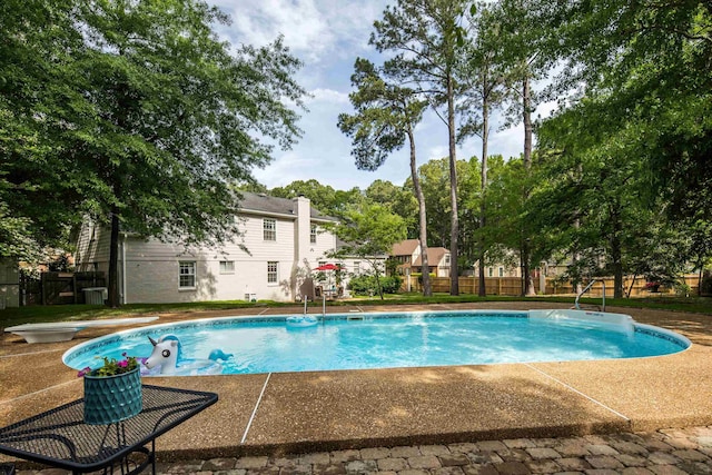 view of swimming pool with a fenced in pool, fence, a diving board, and a patio