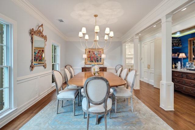 dining area with an inviting chandelier, ornamental molding, visible vents, wood finished floors, and ornate columns