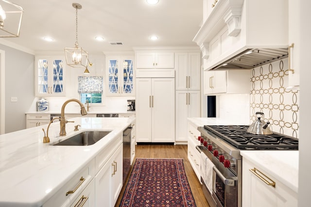 kitchen featuring high end appliances, a sink, premium range hood, a chandelier, and recessed lighting
