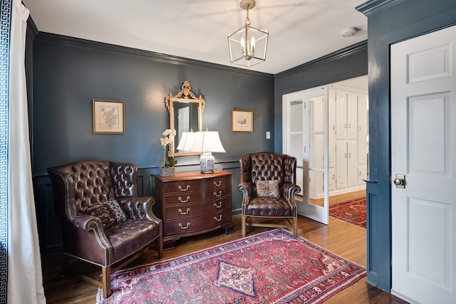 sitting room featuring ornamental molding, wood finished floors, and a notable chandelier