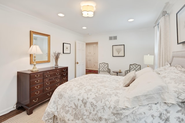 bedroom featuring visible vents, crown molding, wood finished floors, baseboards, and recessed lighting