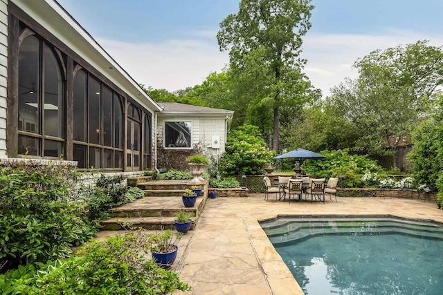 outdoor pool featuring outdoor dining space, a sunroom, and a patio area