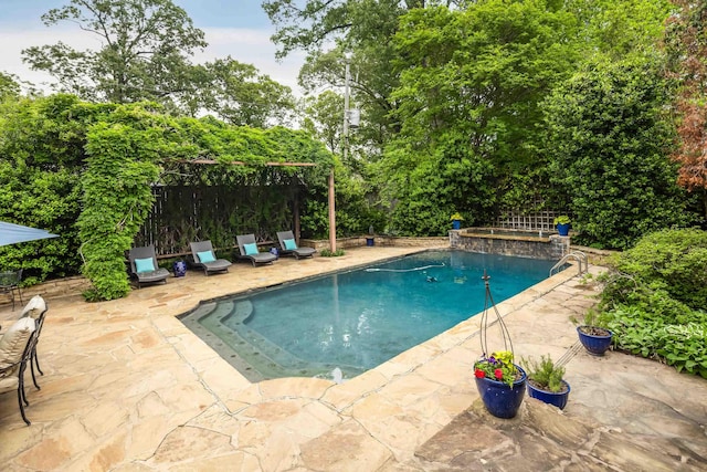 outdoor pool with fence and a patio area