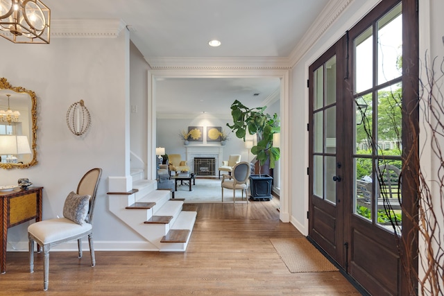 entryway with baseboards, ornamental molding, wood finished floors, and a notable chandelier