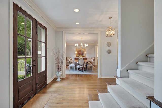 entryway with crown molding, baseboards, an inviting chandelier, and stairway