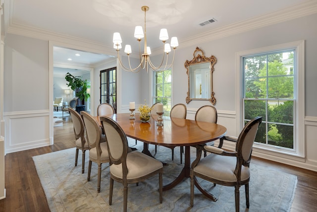 dining room featuring visible vents, crown molding, dark wood finished floors, a wainscoted wall, and a chandelier