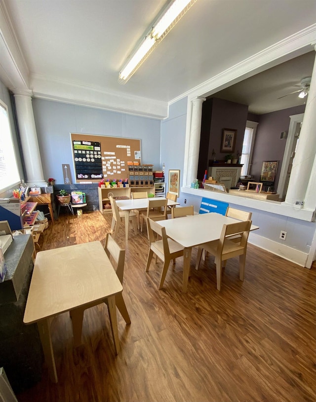 recreation room with ceiling fan, ornamental molding, decorative columns, and wood finished floors