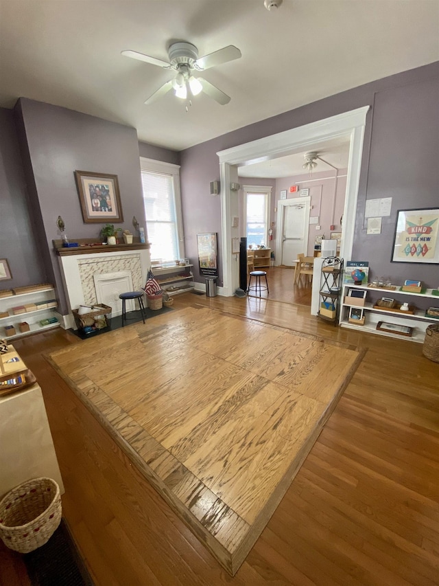 living area with a ceiling fan and wood finished floors