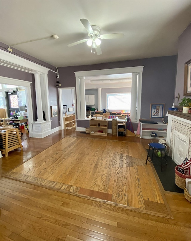 living room featuring hardwood / wood-style flooring, a ceiling fan, and ornate columns