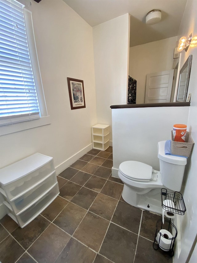 bathroom with baseboards, a walk in shower, toilet, and tile patterned floors