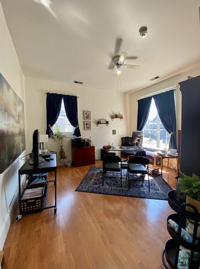 interior space with ceiling fan, visible vents, plenty of natural light, and wood finished floors
