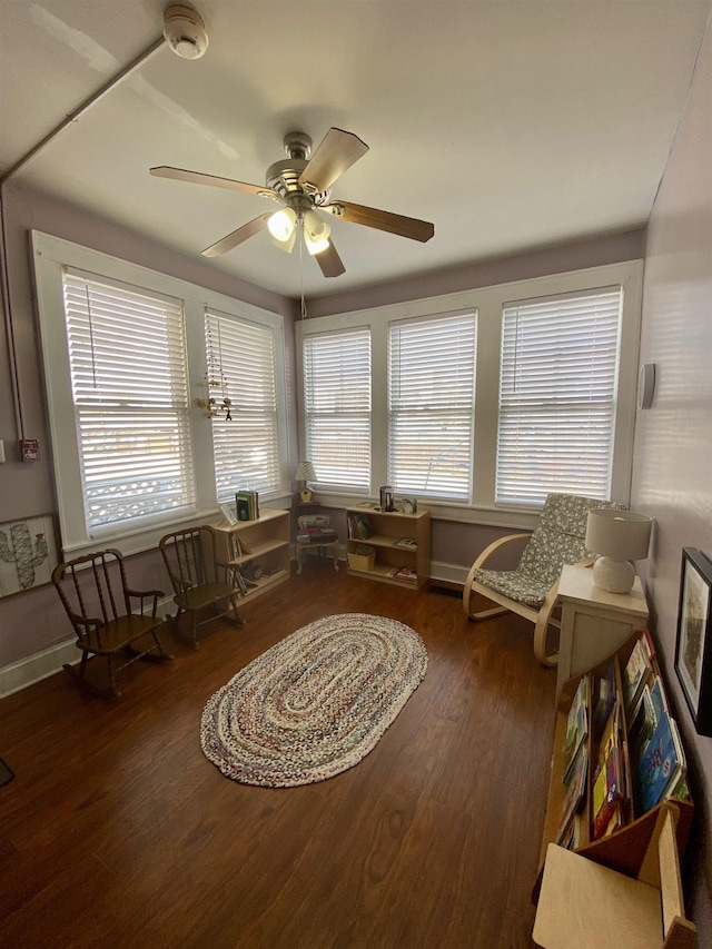 living area with baseboards, ceiling fan, and wood finished floors