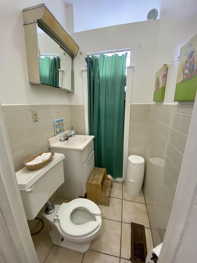 full bath featuring tile walls, tile patterned floors, wainscoting, and toilet