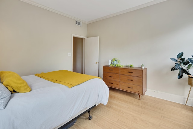 bedroom with crown molding, baseboards, light wood-type flooring, and visible vents