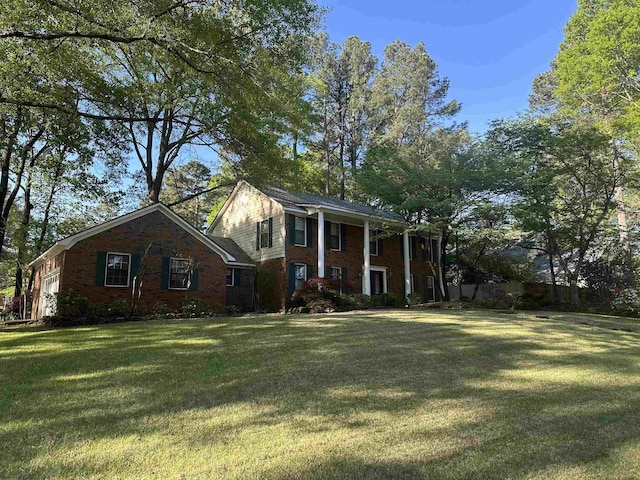 greek revival inspired property with an attached garage, a front yard, and brick siding