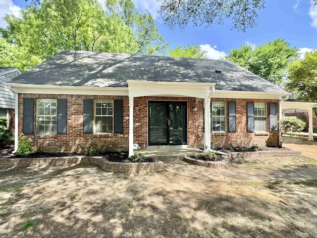 view of front of home with brick siding, french doors, and roof with shingles