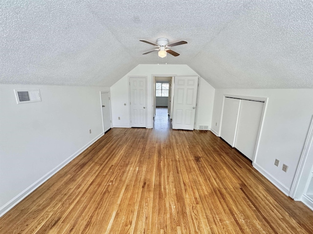 bonus room with baseboards, a textured ceiling, and visible vents