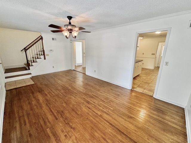 unfurnished living room with visible vents, stairs, ceiling fan, light wood-type flooring, and a textured ceiling