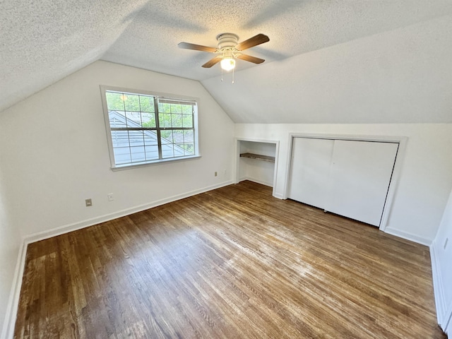 bonus room with a textured ceiling, ceiling fan, wood finished floors, and vaulted ceiling