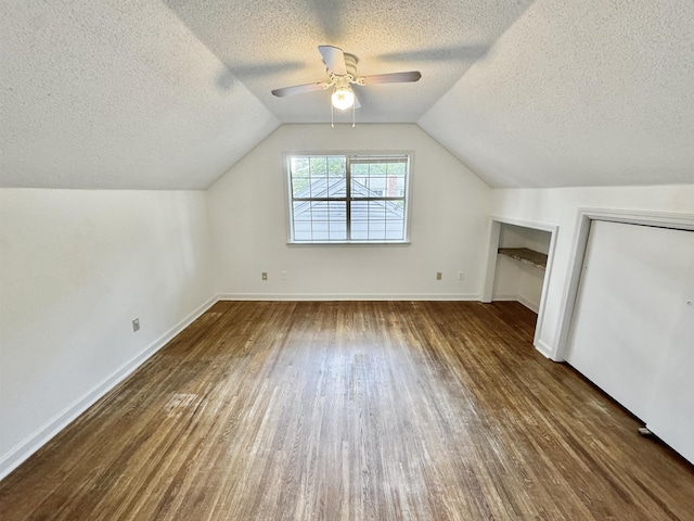 bonus room featuring ceiling fan, a textured ceiling, wood finished floors, baseboards, and lofted ceiling