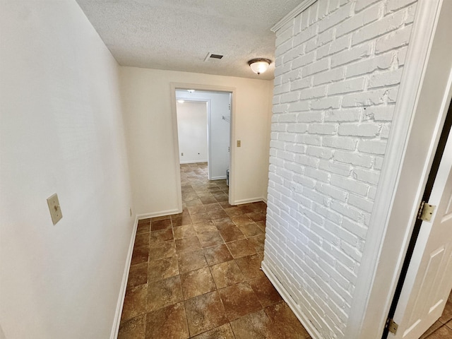 corridor featuring visible vents, a textured ceiling, and baseboards