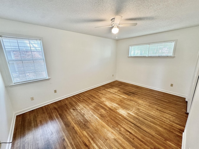 empty room with plenty of natural light, a textured ceiling, ceiling fan, and wood finished floors