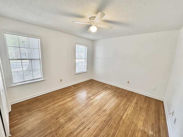 spare room with baseboards, a textured ceiling, ceiling fan, and wood finished floors