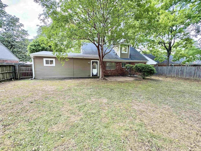 back of house with a fenced backyard, a patio, and a lawn
