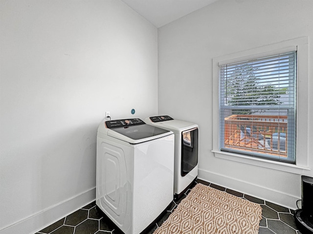 washroom with washer and dryer, dark tile patterned flooring, laundry area, and baseboards
