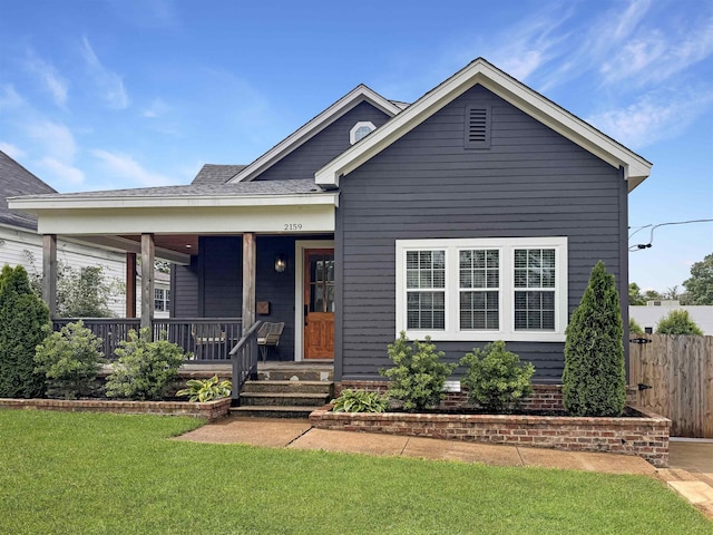 view of front of property featuring covered porch, fence, and a front yard