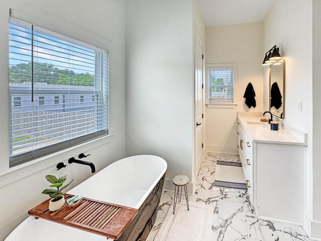 full bath with baseboards, marble finish floor, vanity, and a soaking tub