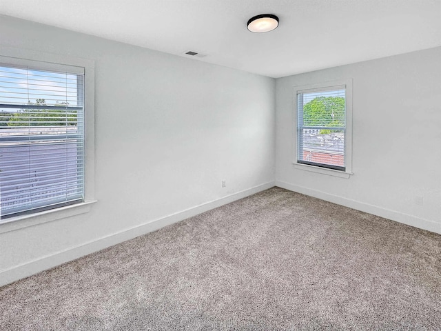 carpeted spare room featuring baseboards and visible vents