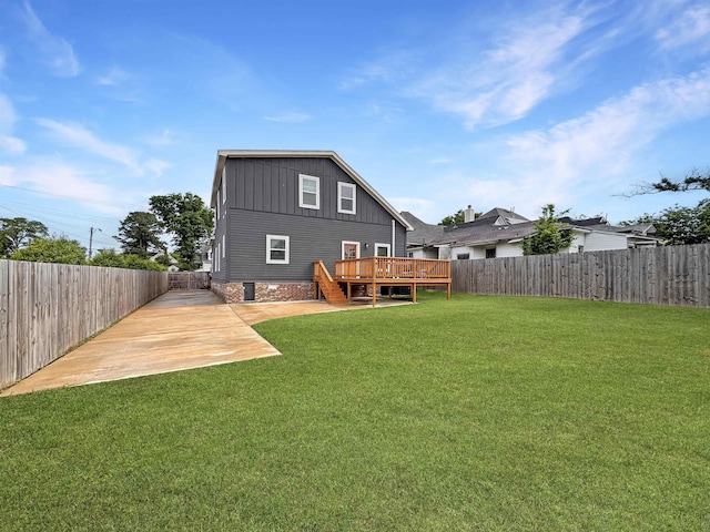 back of house with a fenced backyard, a wooden deck, board and batten siding, and a yard
