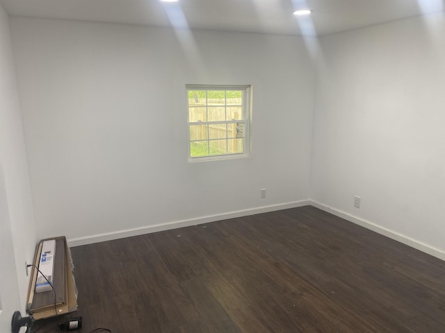 unfurnished room with baseboards and dark wood finished floors
