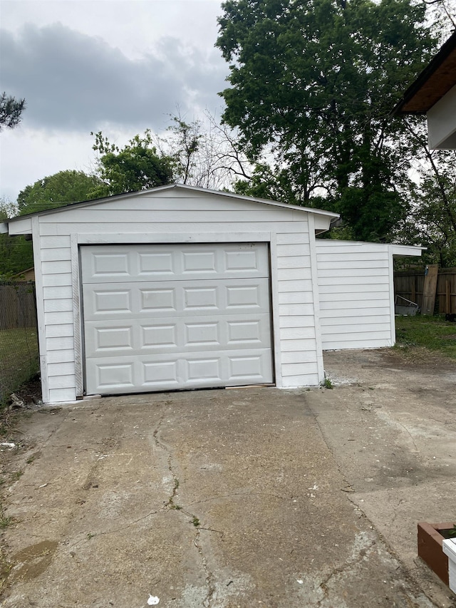 detached garage featuring fence and concrete driveway