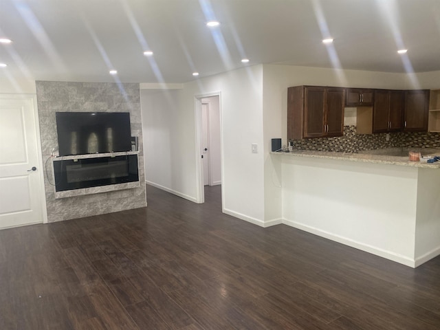 unfurnished living room with recessed lighting, baseboards, a fireplace, and dark wood-style flooring