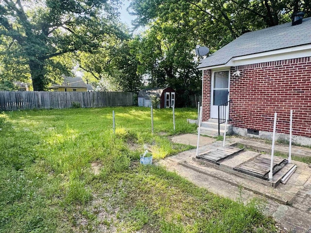 view of yard featuring fence, an outdoor structure, entry steps, and a storage shed