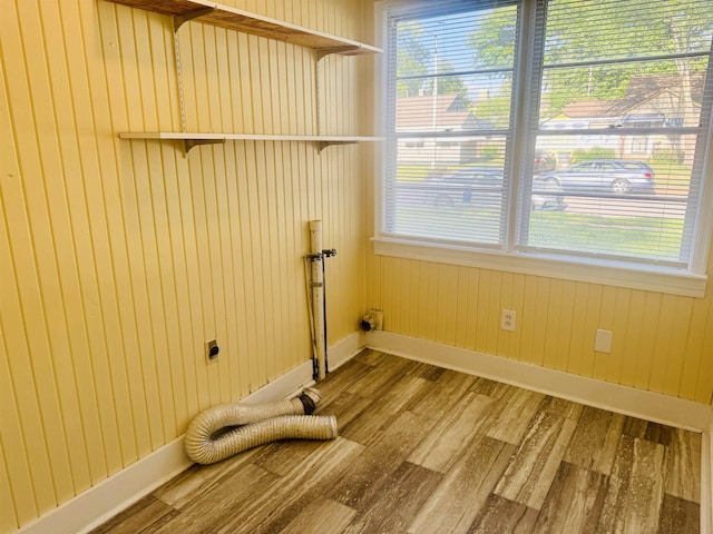 laundry room featuring laundry area, wood finished floors, baseboards, wooden walls, and hookup for an electric dryer