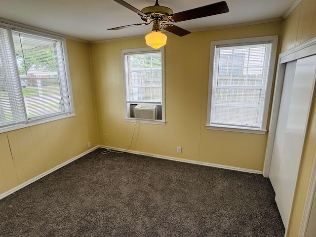 empty room with ornamental molding, dark carpet, baseboards, cooling unit, and a ceiling fan