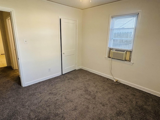 spare room featuring baseboards, cooling unit, and dark carpet