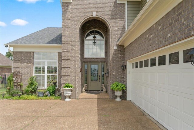 235 Fairoaks Dr, Oakland, TN 38060 - property entrance featuring a garage, a shingled roof, driveway, and brick siding