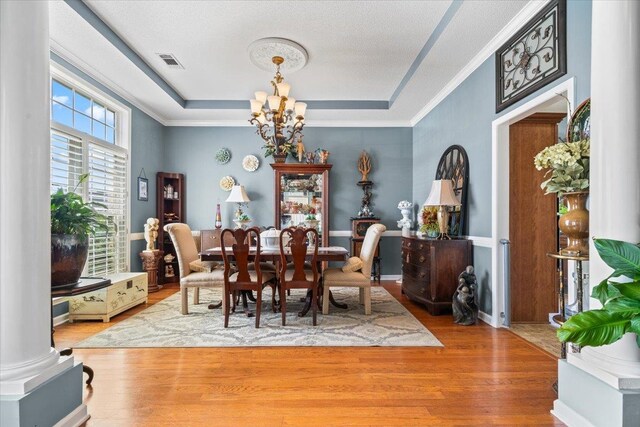 235 Fairoaks Dr, Oakland, TN 38060 - dining area with visible vents, wood finished floors, a raised ceiling, an inviting chandelier, and ornate columns